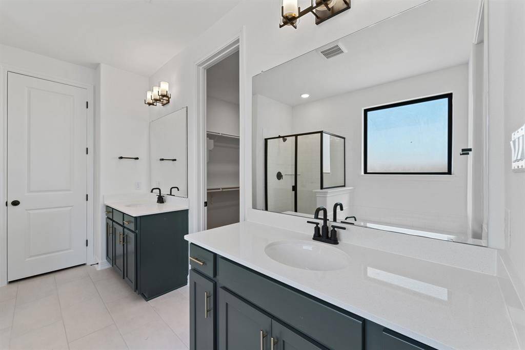The en-suite bathroom offers a spa-like atmosphere with its elegant design, high end finishes, and tasteful lighting, creating a retreat within your own home.