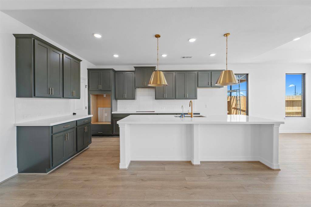 This light and bright kitchen features a large quartz island, custom painted cabinets, a large sink overlooking your family room, recessed lighting, and beautiful backsplash.
