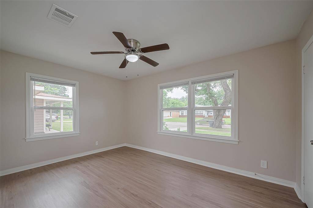 Awash in natural light, this tranquil bedroom offers large windows, neutral tones, and a ceiling fan overhead—maintaining the home’s clean, modern aesthetic throughout.