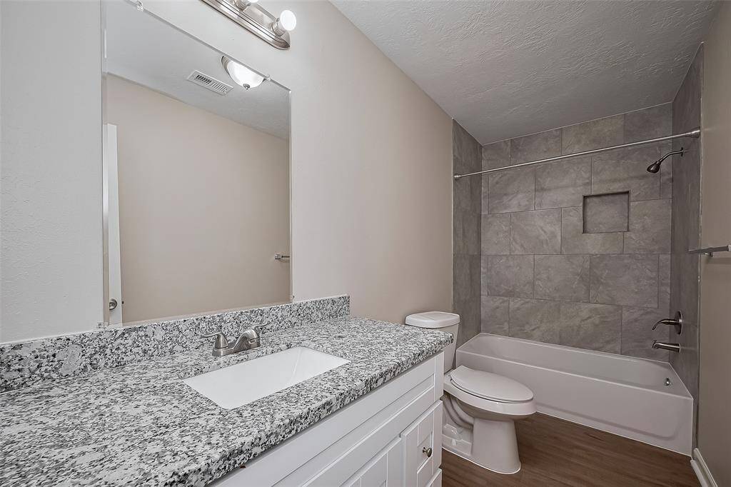 The primary en suite offers everyday luxury with a wide vanity, abundant storage, and tasteful tilework surrounding the tub-shower combination. Thoughtful lighting and clean finishes complete the look.