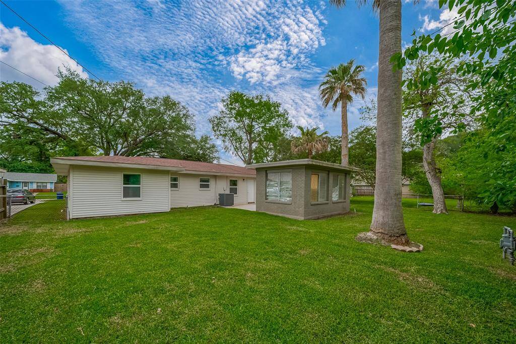 The backyard offers a serene, expansive outdoor setting with vibrant grass and the shade of mature trees. There’s ample space to play, garden, or simply unwind in your own private escape.