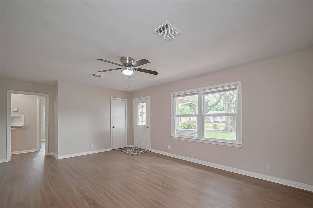 Step inside to a generously sized living area filled with natural light from a wide window. Sleek vinyl plank flooring flows throughout, and a ceiling fan adds year-round comfort. The layout transitions easily into the adjacent kitchen.