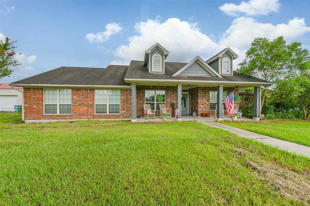 Charming single-story brick home featuring a welcoming front porch, gabled rooflines, nestled on a lush green lawn.
