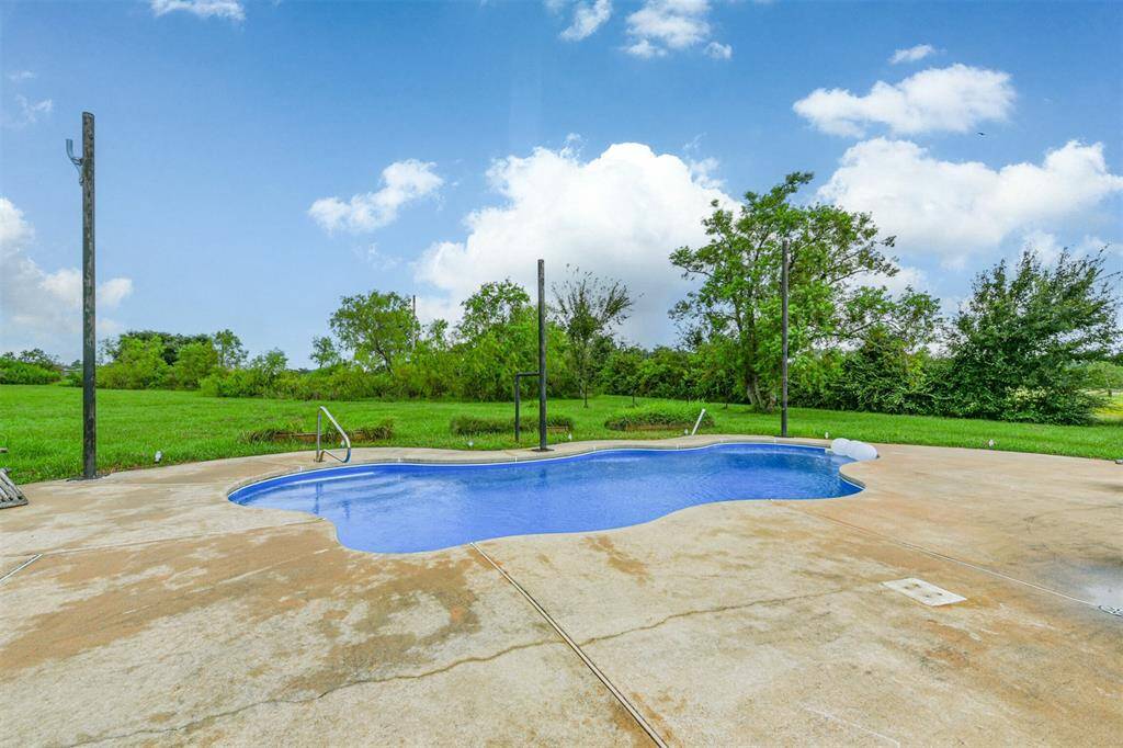 This is a spacious outdoor area featuring a kidney-shaped in-ground swimming pool with surrounding concrete deck.  Perfect for outdoor relaxation and entertaining.
