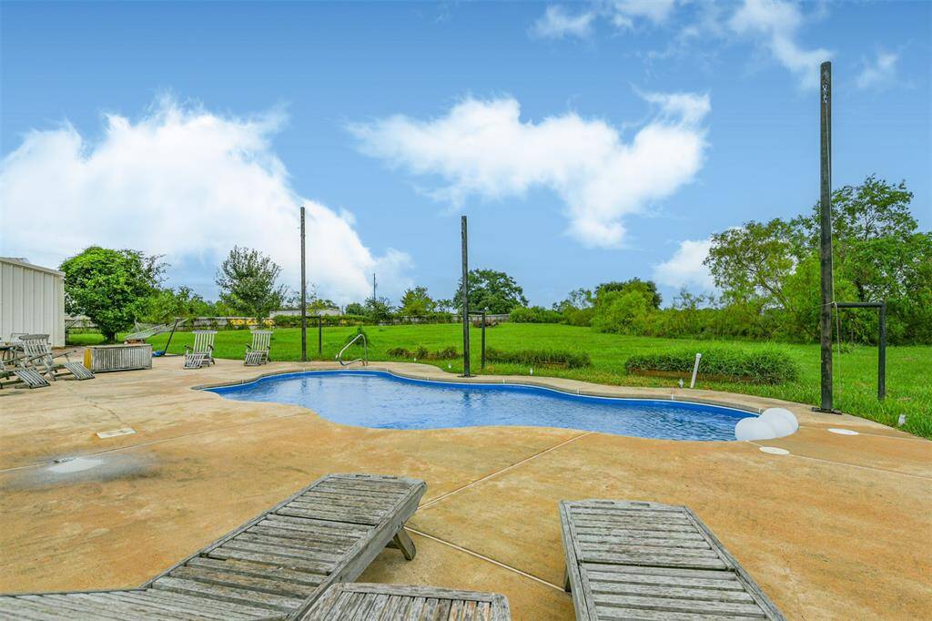 You're looking at a private backyard with an inviting in-ground pool, surrounded by a spacious concrete deck and a serene, open green landscape. It's a perfect blend of leisure amenities and natural beauty.