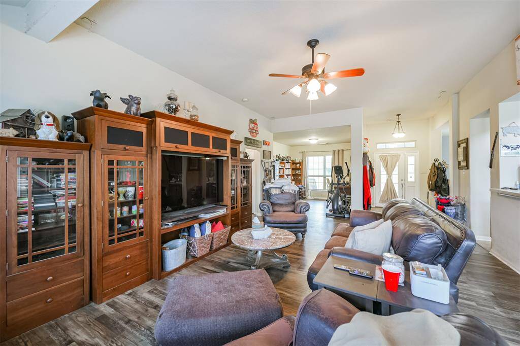 This is a spacious, well-lit living room featuring wood flooring, a ceiling fan.