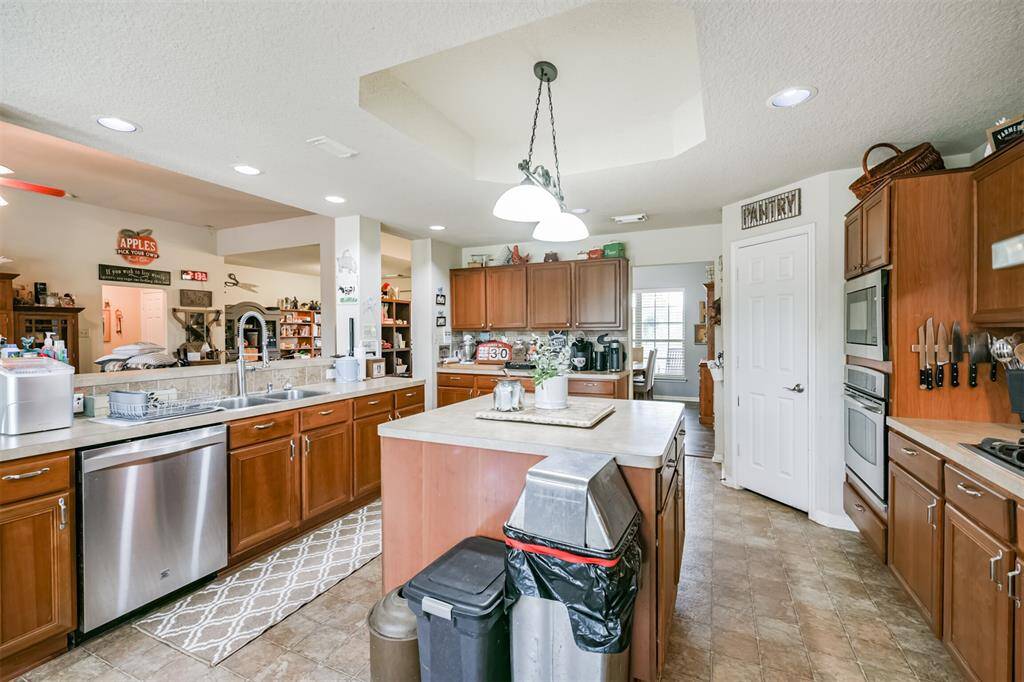 This is a spacious kitchen with ample cabinet space, stainless steel appliances, tiled flooring, and a central island. It also features a pantry for additional storage.