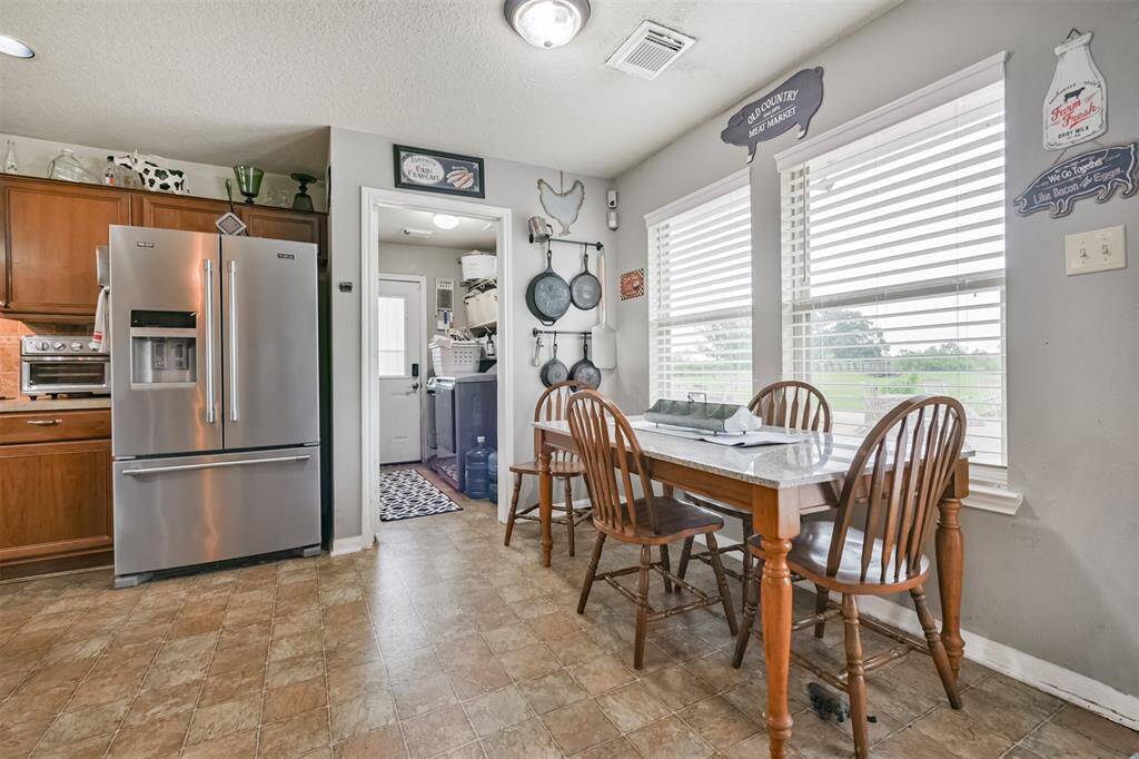 This is a cozy kitchen with modern stainless steel appliances, ample wooden cabinetry, and a dining area with a window view of the pool. The space features tiled flooring and a neutral color palette.