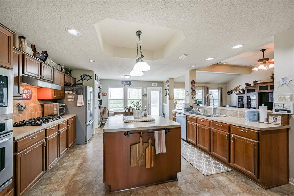 This is a spacious kitchen with ample cabinet space, modern appliances, and a central island. The room features tiled flooring, recessed lighting, and a comfortable dining nook with a view from the window.