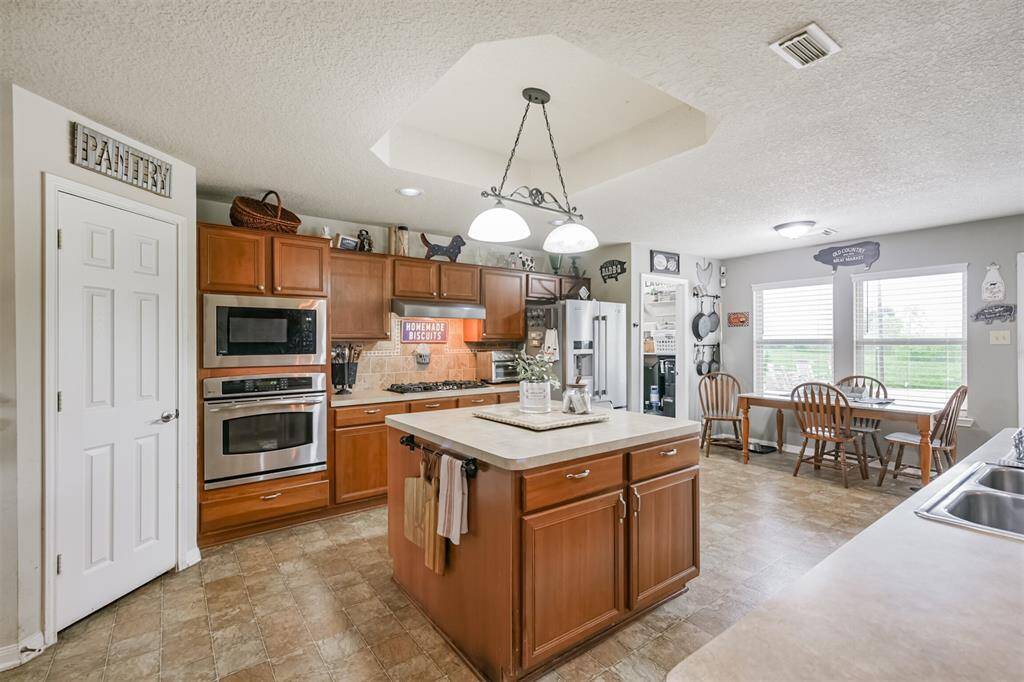 This is a spacious kitchen with modern appliances, ample cabinetry, a central island, a pantry, and an adjoining dining area with plenty of natural light.