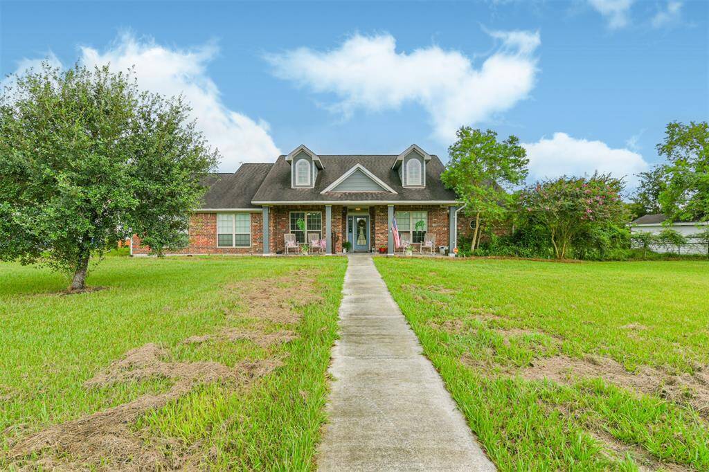Charming single-story brick home with a welcoming front porch, symmetric gabled roof, and a spacious front lawn with mature trees, offering a blend of curb appeal and comfortable living.