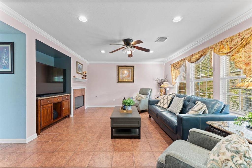 Bright and spacious family room, large windows that flood the space with natural light, a ceiling fan for comfort, and a cozy fireplace—perfect for relaxing and entertaining."