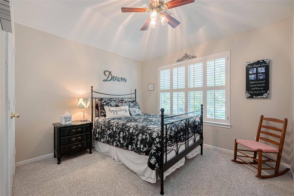 Spacious secondary bedroom featuring elegant Plantation shutters, a ceiling fan, and plenty of natural light