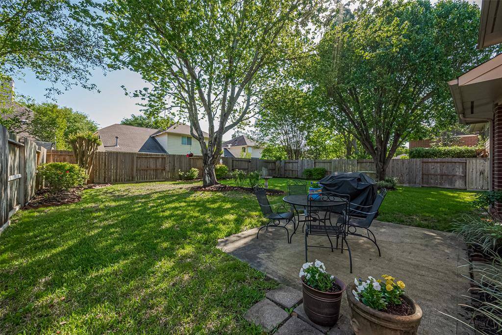 A spacious backyard offers plenty of room to roam, with mature trees that mirror the beauty of the front yard