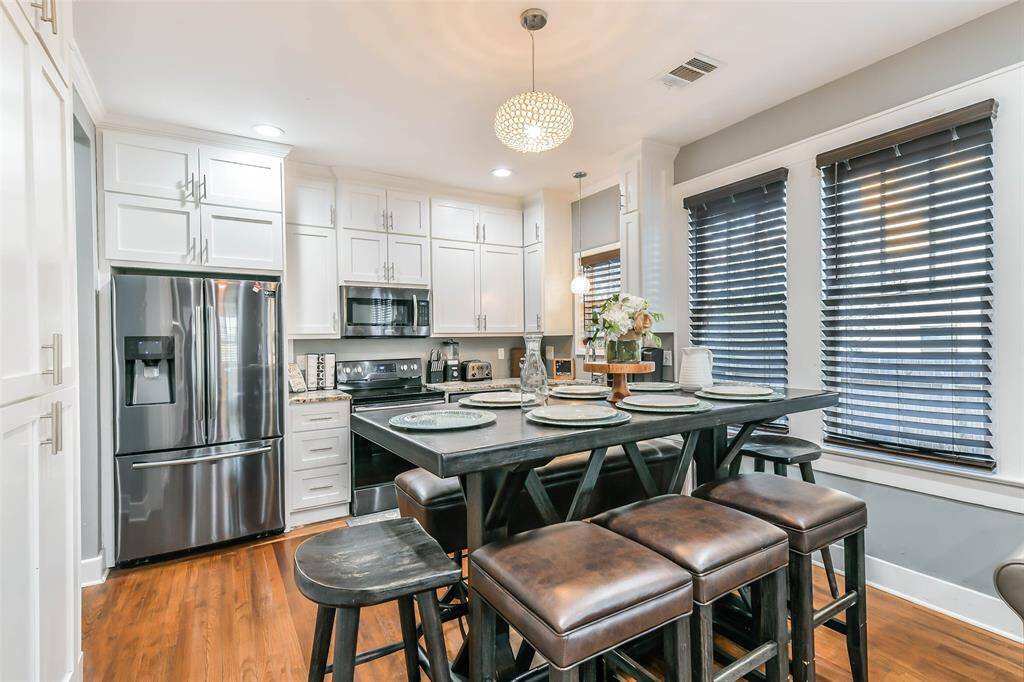 A combined dining and kitchen area featuring tall cabinets adorned with crown molding.