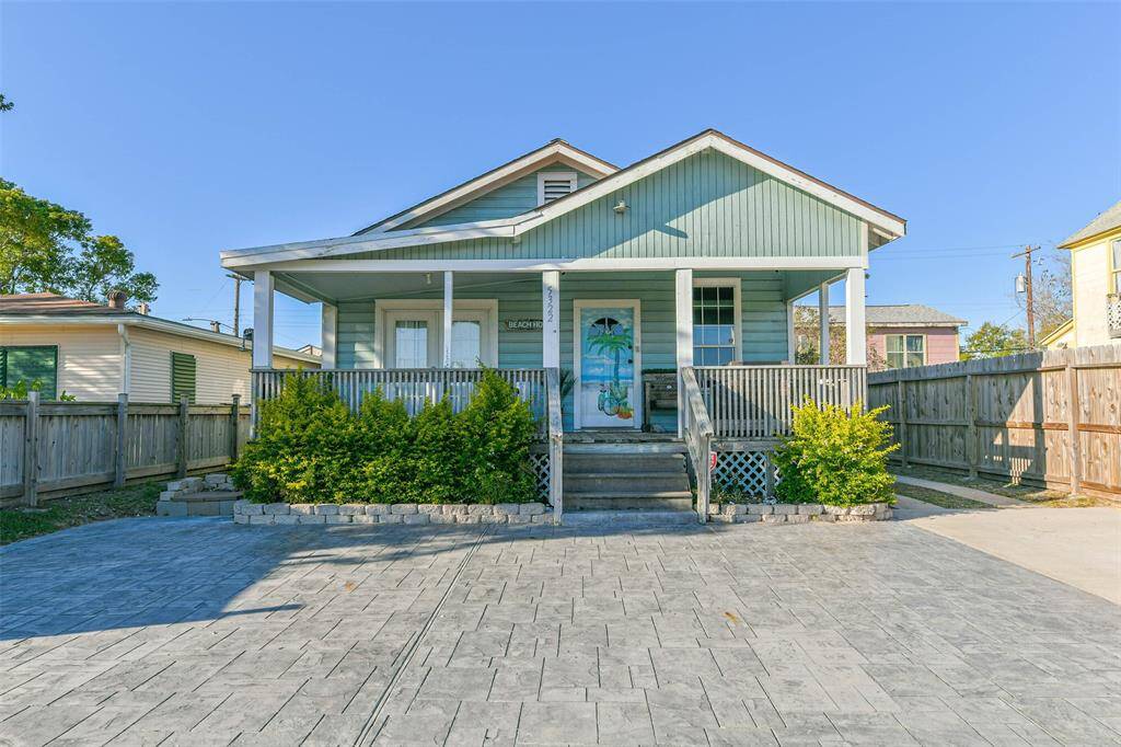 A home featuring a charming covered front porch and plenty of parking space.