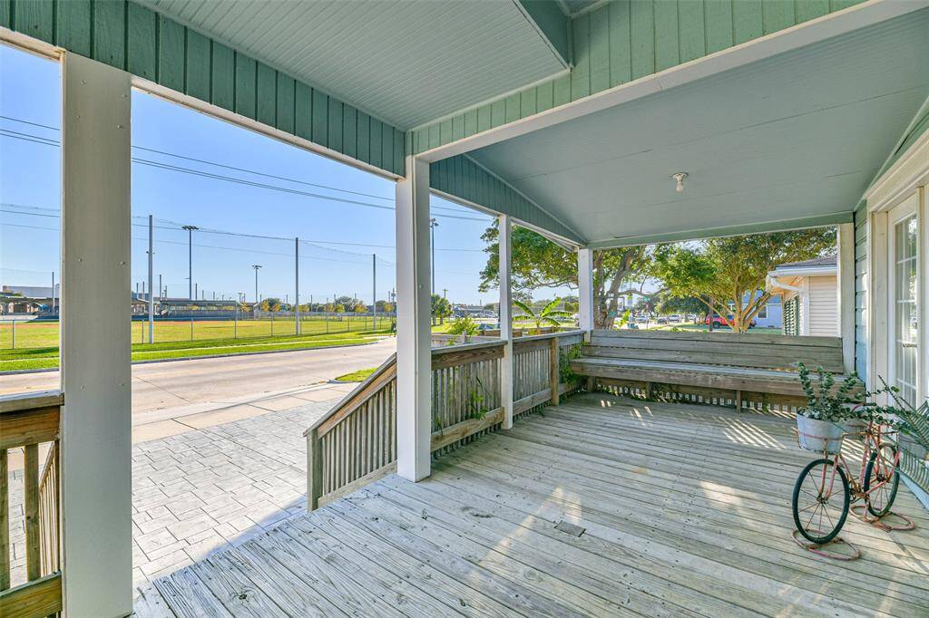 A front porch featuring wood decking, seating, and open wood railings.