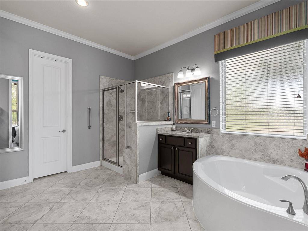 This is a spacious, open-concept living area with a modern kitchen in the background. It features a cozy fireplace, ceiling fan, and stylish decor, creating a warm and inviting atmosphere. The room is well-lit with ample natural light, enhancing the elegant design.