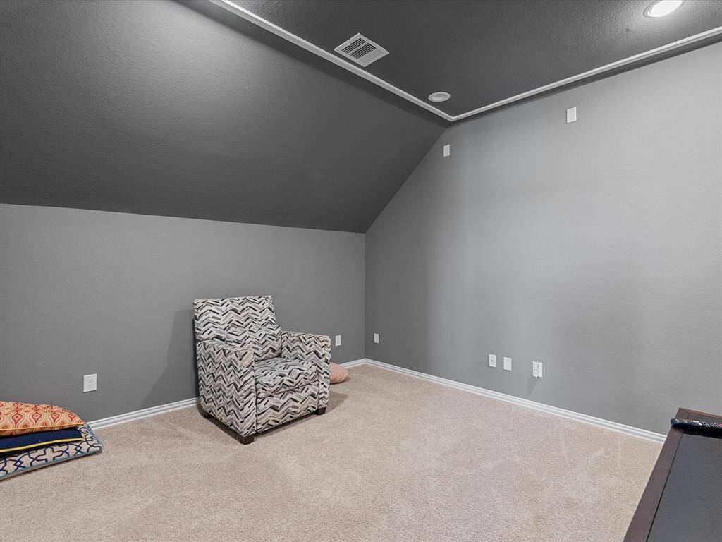The media room features sloped ceilings and gray walls, creating a cozy atmosphere. Its neutral carpet complements the room's calm aesthetic.
