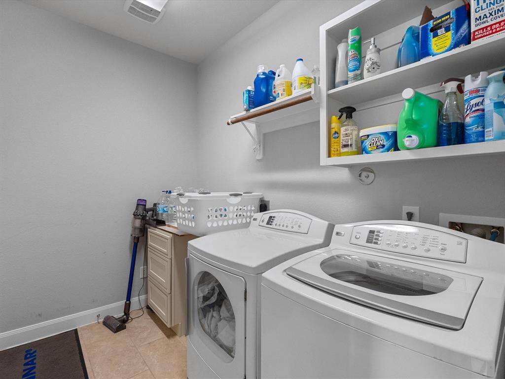 This photo features a bright laundry room with a washer and dryer, ample shelving for storage, and a compact utility area, making it convenient for household tasks.