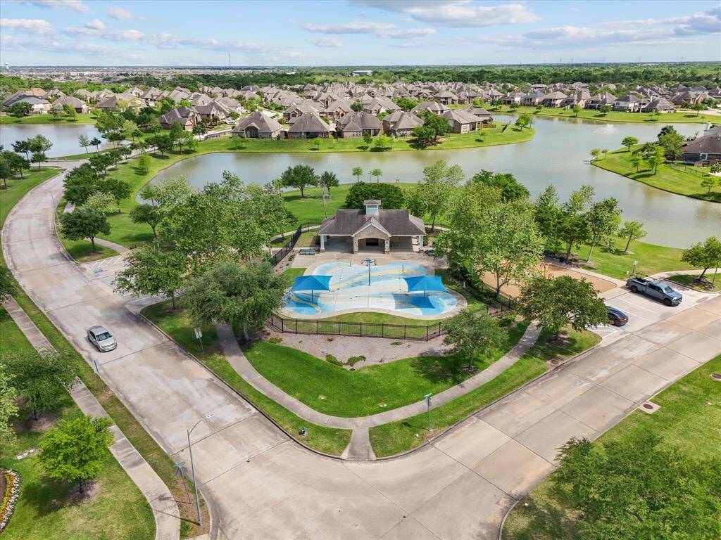 This photo showcases a picturesque neighborhood featuring a community pool, surrounded by lush greenery and walking paths. The area includes scenic water views with houses lining the tranquil lakes, offering a serene, family-friendly environment.