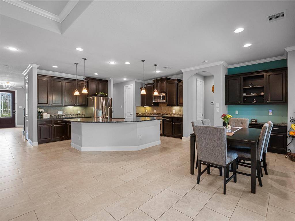 This photo showcases a welcoming entryway with a stylish glass door, leading to a spacious hallway. It features elegant tile flooring, a carpeted area, and a staircase with decorative railing. The space is bright, modern, and has a contemporary chandelier, creating a warm and inviting atmosphere.