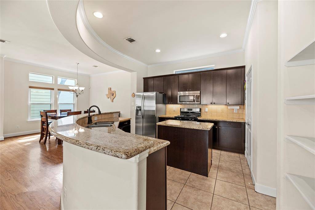 Your chef-inspired kitchen is ready to elevate your culinary experiences! This stunning space offers exquisite granite countertops complemented by a stylish stone backsplash, creating a harmonious blend of elegance and functionality. Equipped with top-of-the-line stainless steel appliances, it invites culinary creativity at every turn. The rich cabinets, adorned with modern hardware, exude sophistication, while the under-cabinet and recessed lighting illuminate the area beautifully.