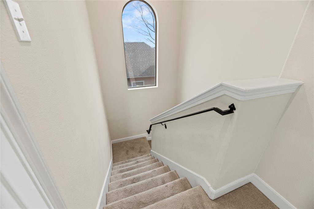 At the top of the third floor, a large window floods the landing with natural light, creating a bright and inviting atmosphere.