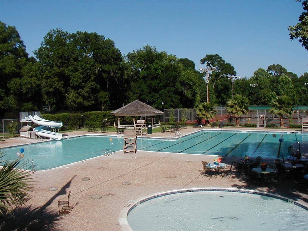 The Club has a grand pool, kiddie pool--and tennis/pickleball courts in the photo's background. The Sharks swim team is always competitive and fun for the kids!