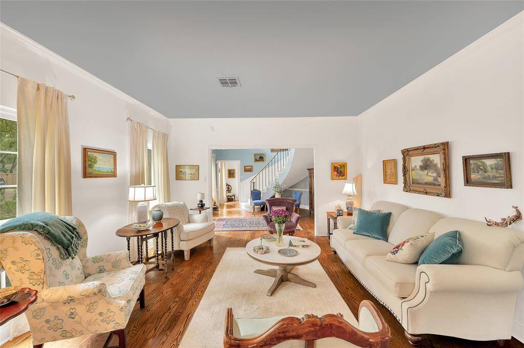 A view from the dining room through the living room to entry with cluster of rooms making up the primary bedroom area in the far background.
