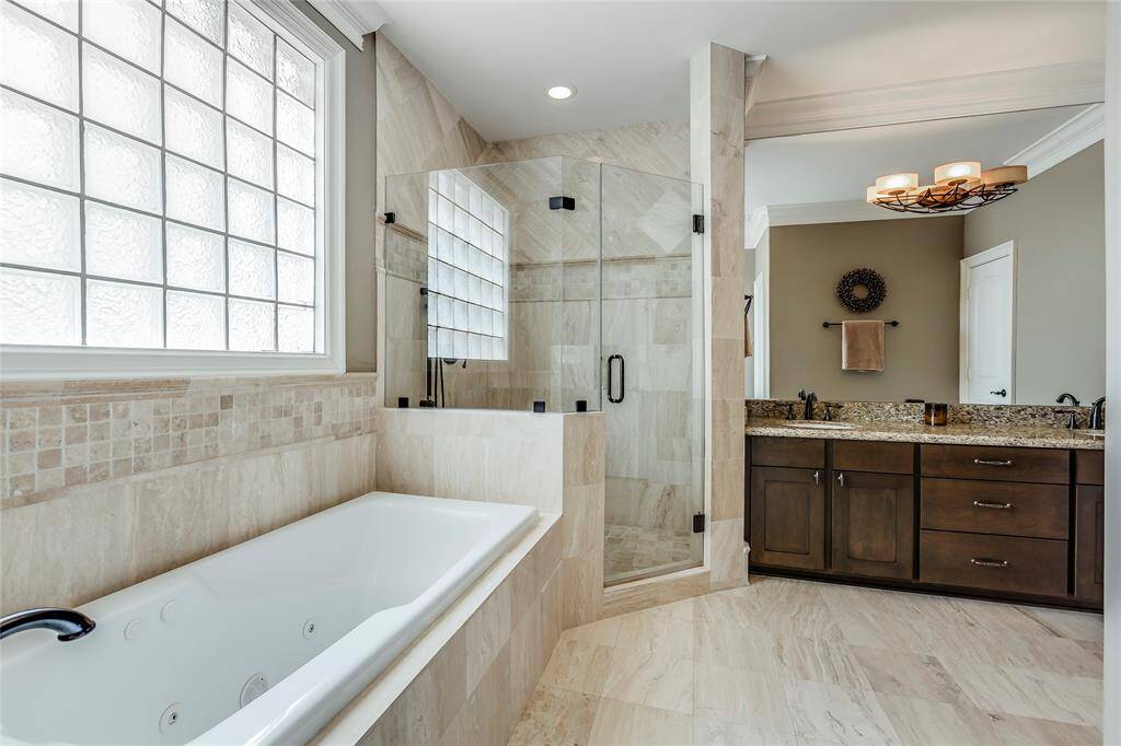 Primary Bathroom with beautiful tile, wooden cabinets, granite counters, seamless shower