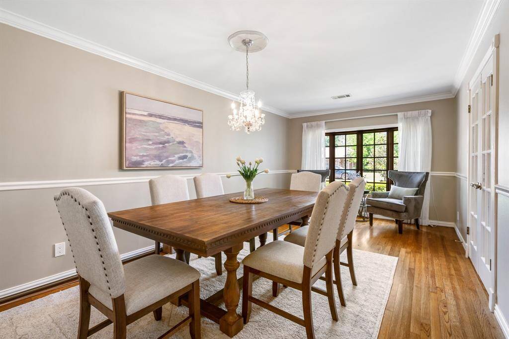 Elegant dining room with hardwood flooring, crown molding, french doors, beautiful bay window, and chandelier.  This rrom is on the front of the house.