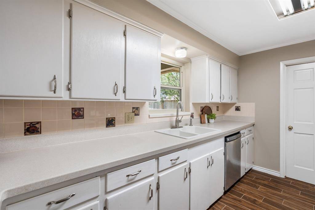 The white cabinets and Corian countertops are both beautiful and functional. Window overlooks the peaceful backyard. Door leads into the utility room.