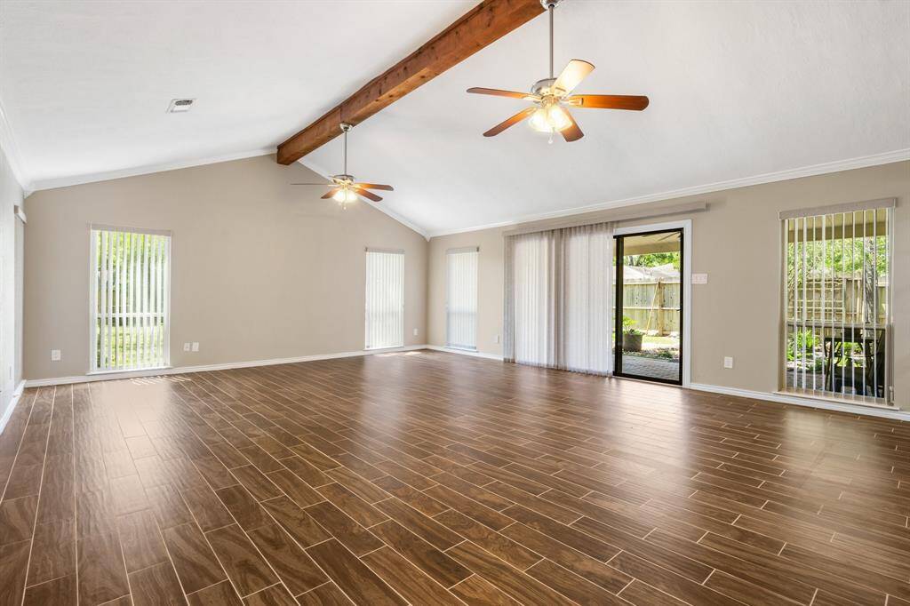 The massive game room is a great place to entertain!  Bring your pool-table! Notice the wooden beam detail  and ceiling fans.  This room is light and bright.  Windows overlook the beautiful backyard.