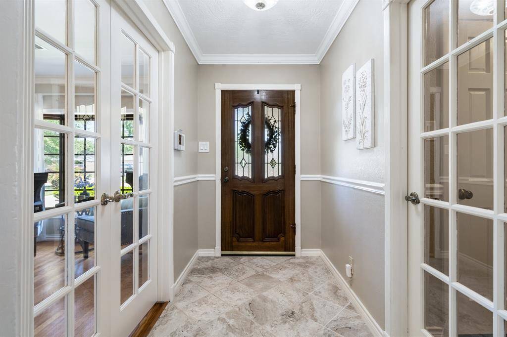 Notice the details! The lovely mahogany front door, crown molding, chair rail and tile floor. The french doors lead into the elegant dining room.