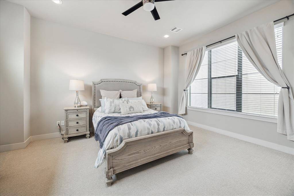 Sleep soundly in the carpeted primary suite, featuring a king-size bedroom topped by a contemporary ceiling fan.