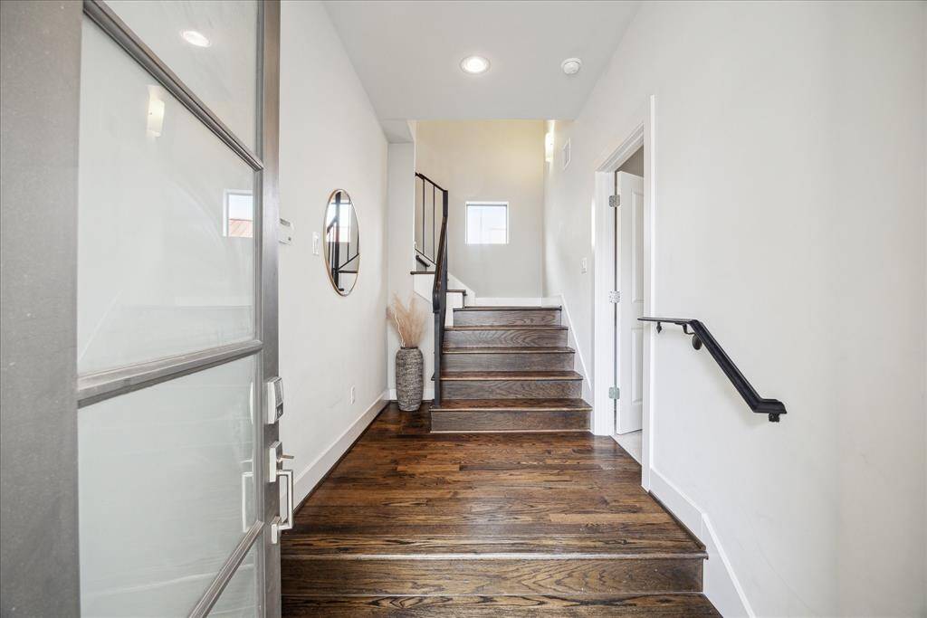 A stylish frosted glass entry door welcomes you inside the 2,199-square-foot home featuring rich hardwood floors, custom blinds, and tall ceilings dotted with recessed lighting.