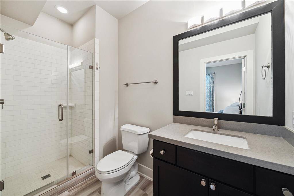 Inside the ground-floor secondary bath, enjoy a roomy quartz vanity and a walk-in glass shower.