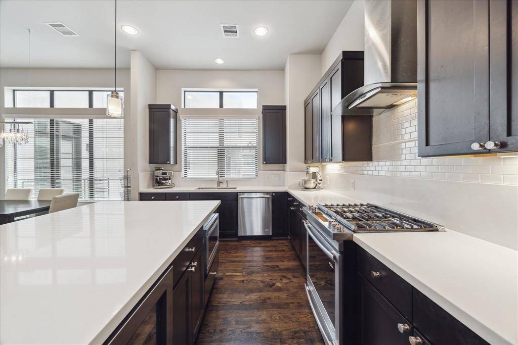 The bright kitchen’s suite of stainless steel appliances includes a vented gas range, dishwasher and microwave drawer by Jenn-Air, plus a side-by-side refrigerator.