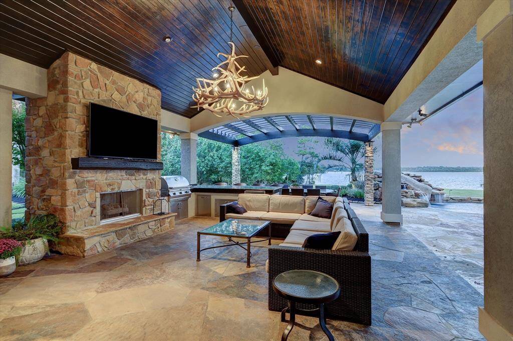 Spacious outdoor living area with a fireplace, TV, and built-in kitchen, perfect for entertaining or relaxing year-round.