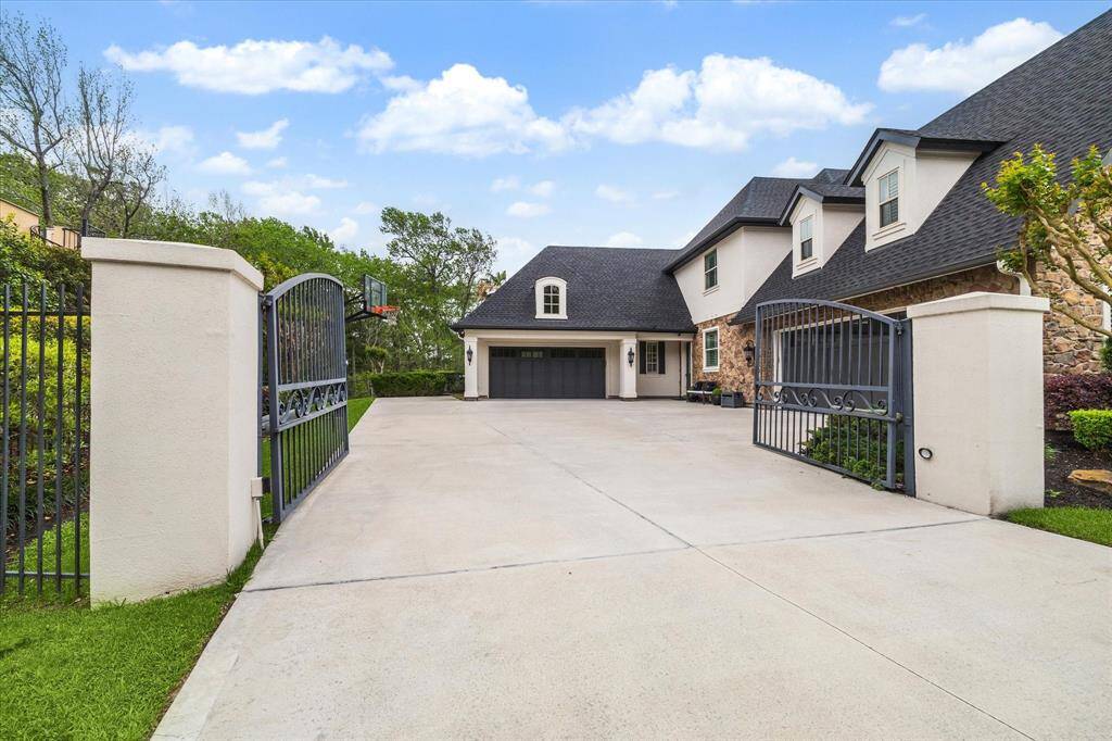 Private driveway with electric gates leading to a spacious motor-court, a 4-car garage with ample storage, whole home generator, and recent upgrades including a new roof and concrete driveway for added convenience and peace of mind.