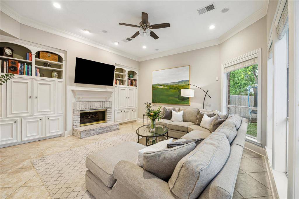 Cozy up to the fireplace for a movie in the family room with custom built-in cabinets and ample windows.
