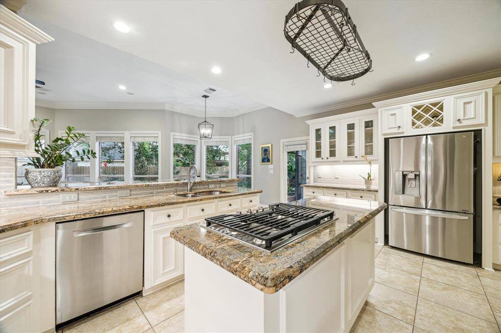 At this center of this gorgeous kitchen is an island with a 5-burner stove and a gourmet pot hanging rack.