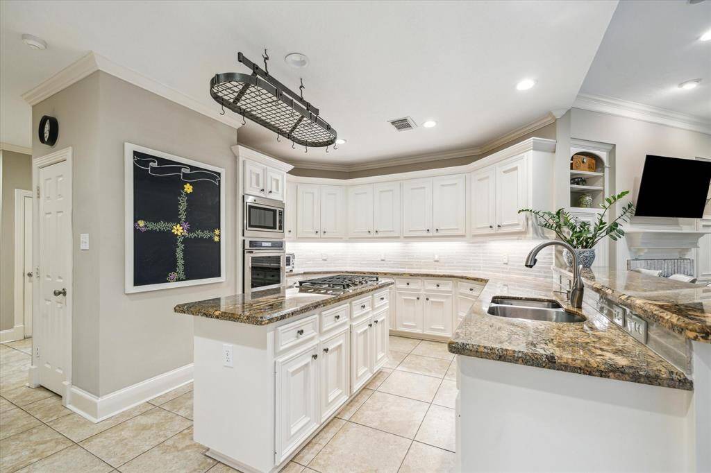 White custom cabinets and rich granite countertops grace this well-appointed chef’s kitchen.