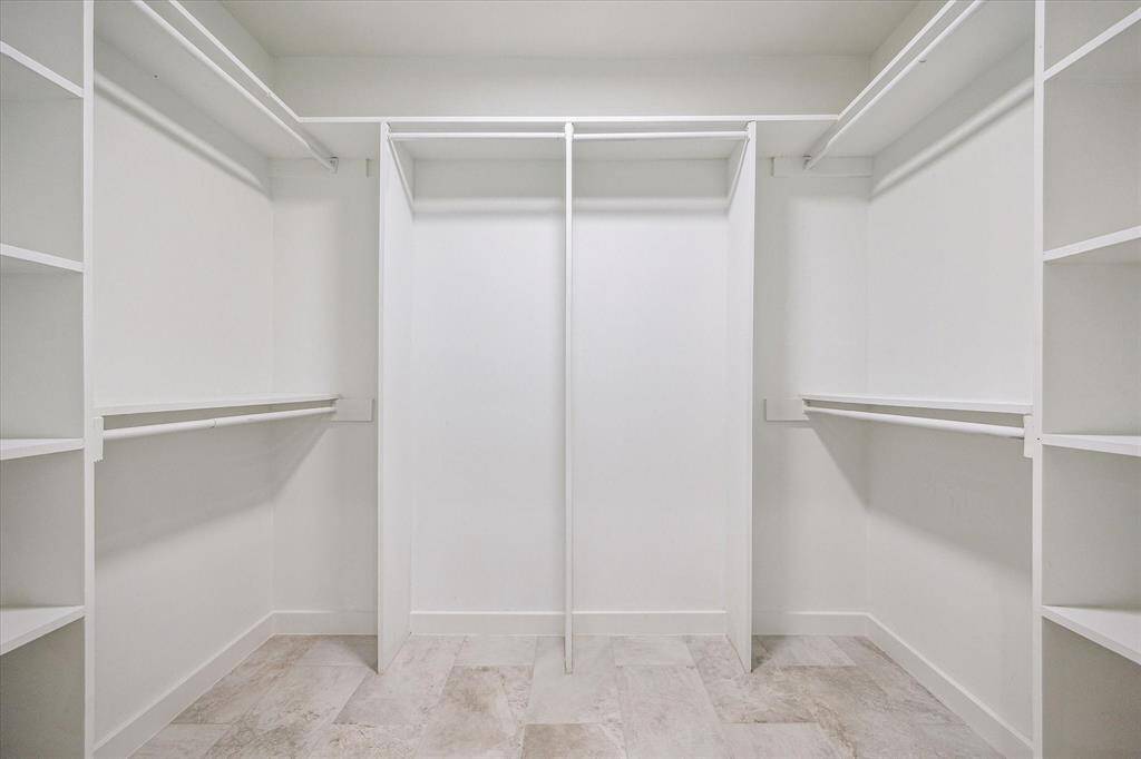 Shop until you drop! This walk-in closet features ample shelving and plenty of space for clothes, shoes, bags, and more.