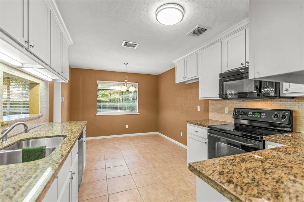 The kitchen is large and has custom cabinets, full extension cabinet drawers, granite counter tops, a deep drop in stainless sink with updated faucet, smooth top electric stove with microwave above.