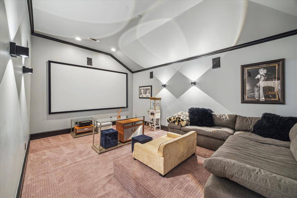 This home theater features a large screen, plush sectional seating, and stylish decor, perfect for movie nights. The room's soft lighting and sound system enhance the cinematic experience.