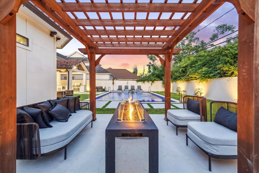 This photo showcases a luxurious outdoor seating area with a pergola overlooking a modern pool. The space is elegantly designed, perfect for relaxing and entertaining.