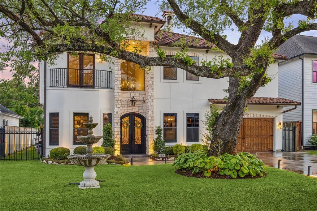 This stunning two-story home features a charming stone facade, elegant wrought iron accents, and a welcoming arched entryway. The lush front yard is highlighted by a beautiful fountain and mature tree, providing a serene and picturesque setting.
