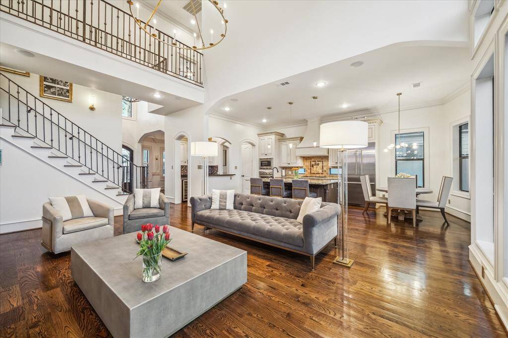 This photo showcases a spacious, open-concept living area with high ceilings, elegant hardwood floors, and a modern kitchen. The room features a stylish staircase, ample natural light, and a chic dining space, perfect for entertaining.